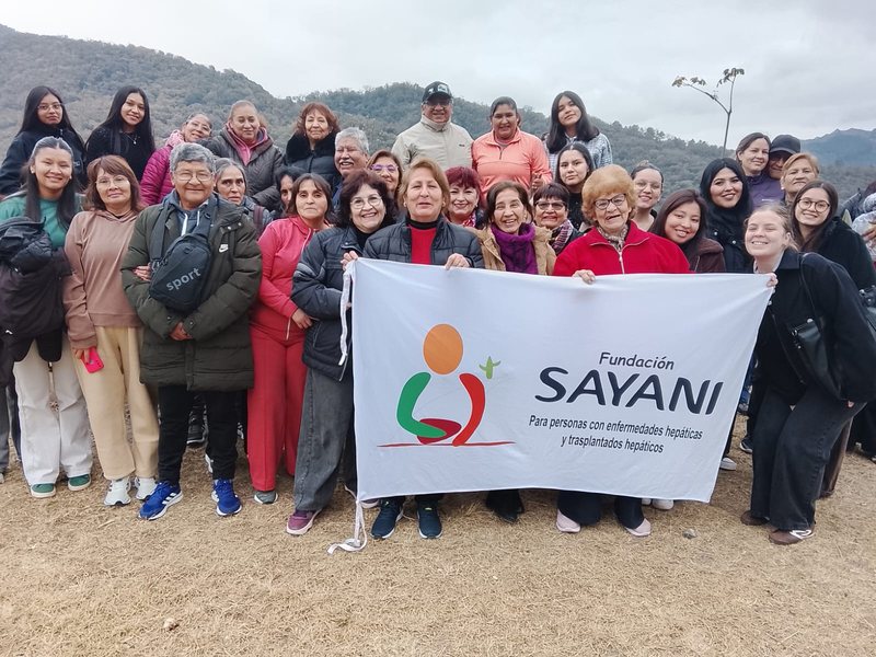 Pacientes y familiares de Fundación Sayani con la bandera institucional en la Quebrada